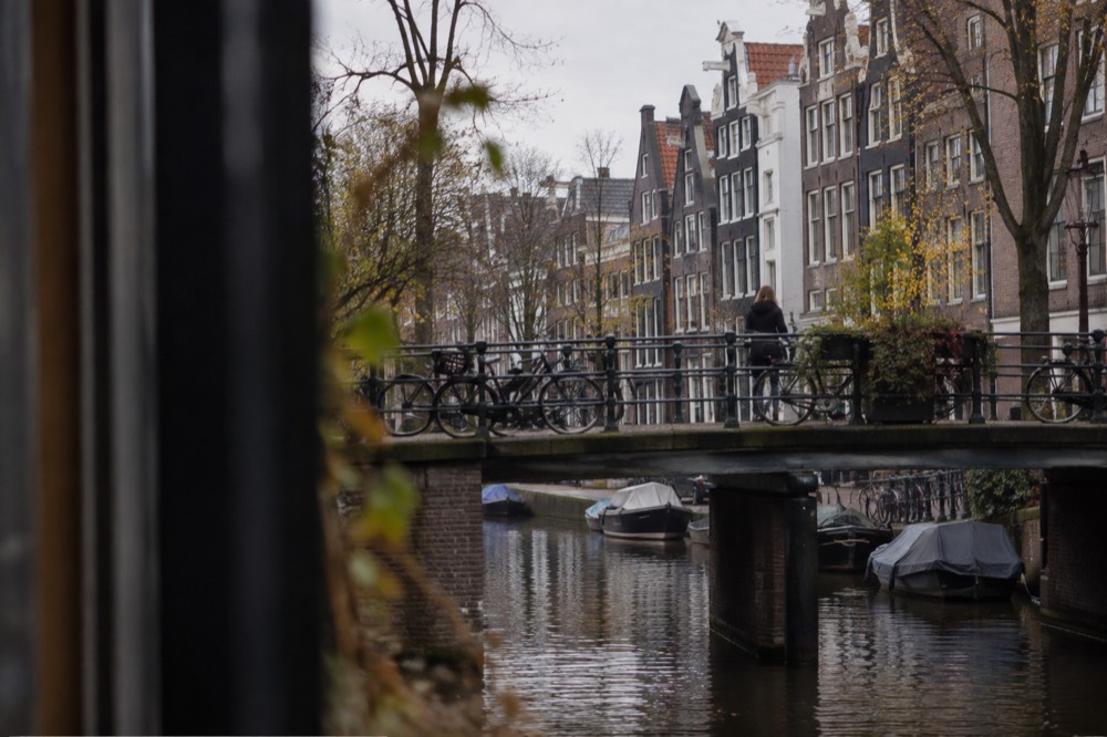 A quiet Amsterdam canal in the Jordaan with narrow gabled houses and bicycles on a bridge