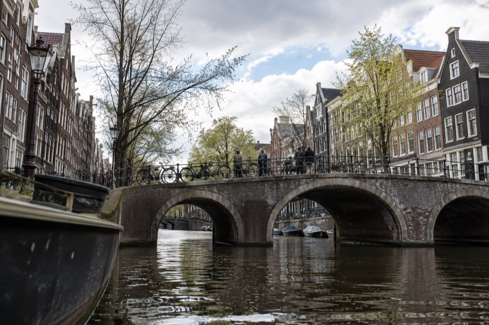 A stone bridge over an Amsterdam canal with narrow gabled houses on both banks