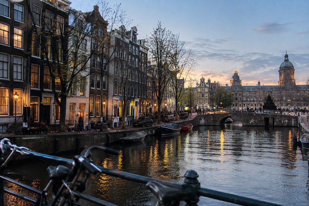 Golden hour light on narrow Amsterdam canal houses seen from a bridge