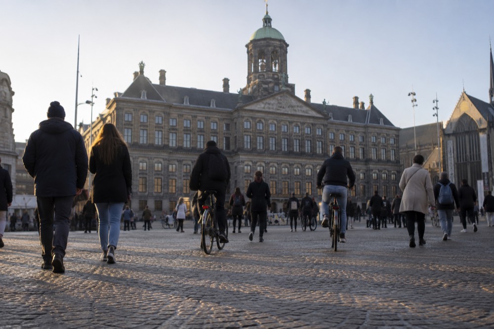 Crowd of pedestrians and bicycles crossing Dam Square in front of the Royal Palace